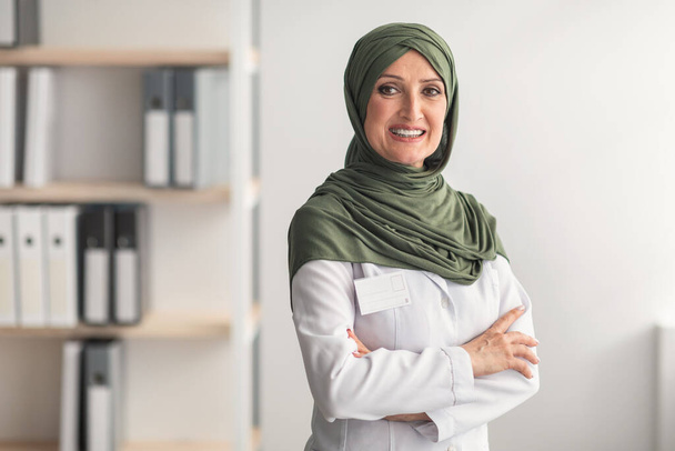 Kypsä muslimi lääkäri nainen yllään hijab poseeraus klinikalla toimistossa - Valokuva, kuva