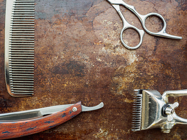 On a rusty surface are old barber tools. Vintage manual hair clipper comb razor shaving hairdressing scissors. Horizontal orientation. - Foto, imagen