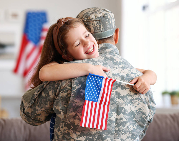 glückliches kleines Mädchen Tochter mit amerikanischer Flagge umarmt Vater in Militäruniform kam von uns Armee, Rückansicht von Vater männlichen Soldaten wieder vereint mit Familie zu Hause - Foto, Bild