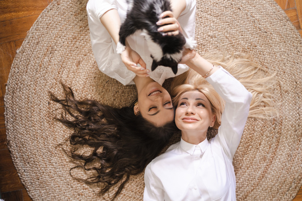 Anne ve kızı kediyle oynarken yerde yatıyorlar. - Fotoğraf, Görsel