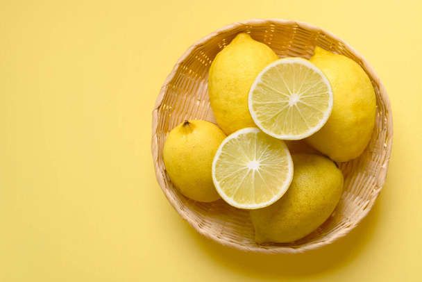 Świeża cytryna w koszyku na żółtym tle, Organiczne owoce cytrusowe, Widok z góry - Zdjęcie, obraz