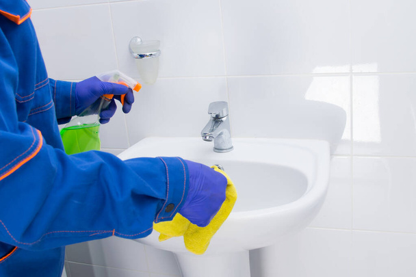 cleaning the bathroom, disinfecting the sink with a cloth and a special tool - Foto, afbeelding