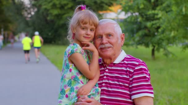 Küçük torun büyükbabasıyla parkta öpüşüyor, mutlu bir aile ilişkisi var. - Video, Çekim