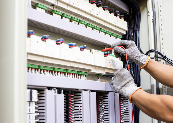 Ingeniero eléctrico prueba el funcionamiento del armario de control eléctrico sobre una base regular para el mantenimiento. - Foto, imagen