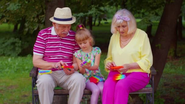 Старшая стильная пара бабушка дедушка с внучкой играют в антистресс поп-это игрушка игра - Кадры, видео