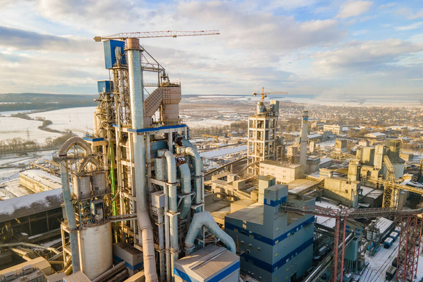 Widok z lotu ptaka cementowni o wysokiej strukturze fabrycznej i żurawia wieżowego na przemysłowym obszarze produkcji. - Zdjęcie, obraz