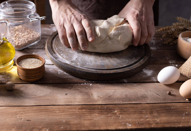 Szef kuchni robi ciasto i składniki piekarnicze do domowej roboty gotowania chleba na stole. Koncepcja piekarnicza i męska ręka - Zdjęcie, obraz