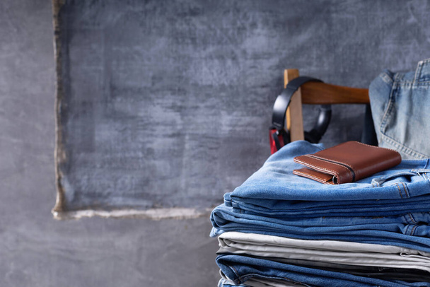 Denim jeans and leather wallet or bag at chair.  Stack of jeans near abstract background texture surface - Fotó, kép
