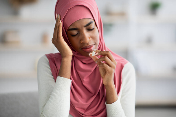 自宅で頭痛に苦しんでいるヒジャブの病気の黒いイスラム教徒の女性 - 写真・画像