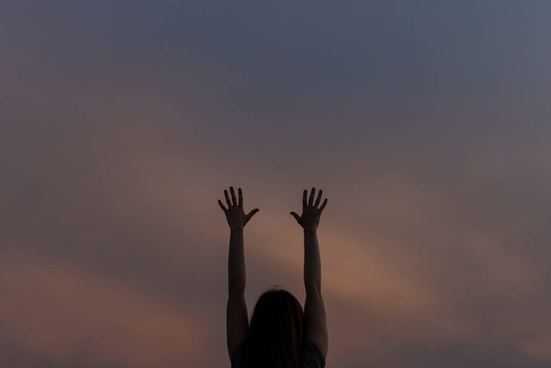 Mulher segura as mãos levantadas contra o fundo do céu da noite. - Foto, Imagem