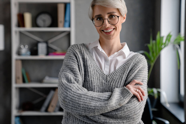 White-haired smiling woman looking at camera while standing in office - Foto, Bild