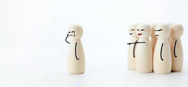 Photographs of the Wooden dolls standing apart from the group and there are illustrations drawings showing the emotion of crying because of being bullied. The concept of being harassed and slander. - Foto, imagen