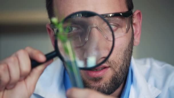 Biochemist looking through magnifying glass - Materiał filmowy, wideo