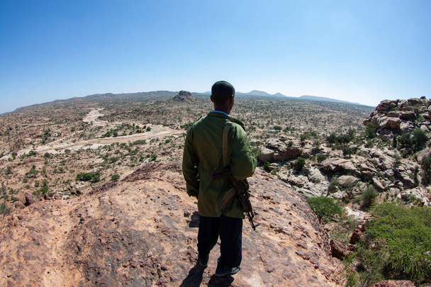 Vista posteriore di una forza di polizia somala che domina la natura selvaggia dalla cima della collina - Foto, immagini
