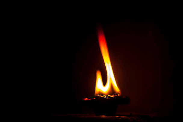 Close-up shot of burning Diva or divida or Diya or oil lamp isolated in dark. - Photo, Image