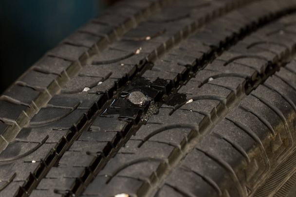 Deep embedded of screw nail on the tire. screw puncturing tire. Tire Tread Nail. Replacing the tires on the car. - Photo, Image