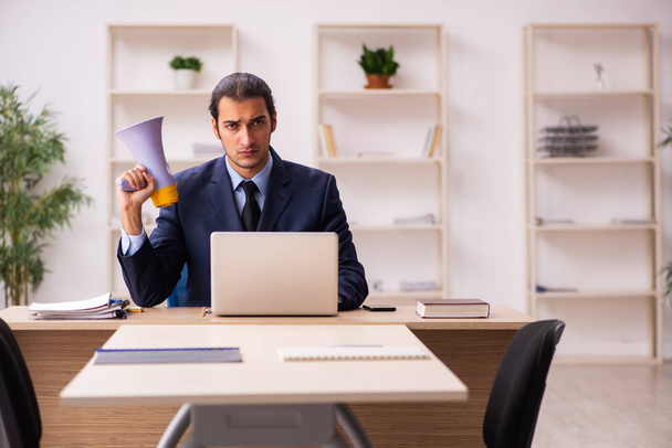 Junger männlicher Arbeitgeber hält Megafon im Büro - Foto, Bild