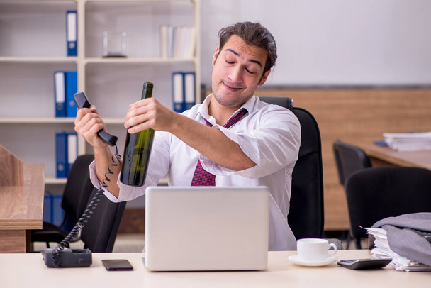 Jeune employé de sexe masculin buvant de l'alcool au bureau - Photo, image