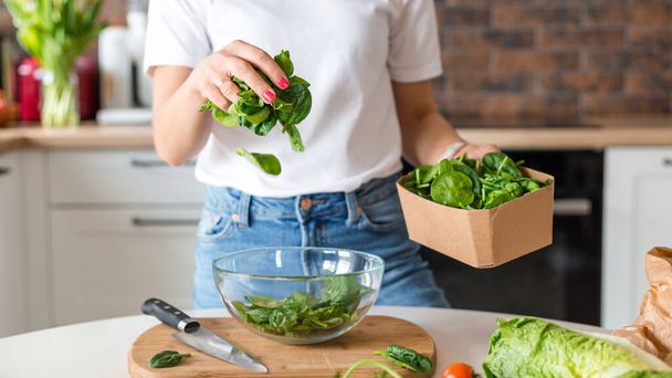Close up woman in white t-shirt cooking salad with motion effect at home kitchen. Process of cooking healthy food, vegetable salad concept. Menu, recipe book banner - 写真・画像
