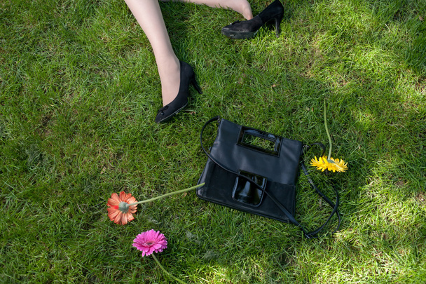 Legs, handbag and flowers on grass - Photo, Image