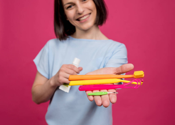 Beautiful young woman uses an oral care kit consisting of a tongue scraper, single tufted and interdental brush - Fotografie, Obrázek