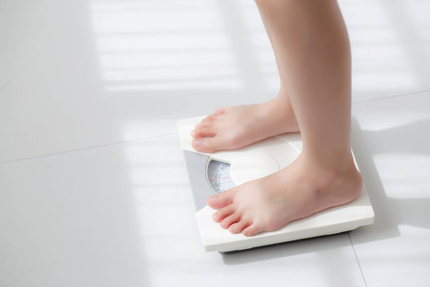 Lifestyle activity with leg of woman stand measuring weight scale for diet with barefoot, closeup foot of girl slim weight loss measure for food control and nutrition, healthy care and wellness concept. - Fotó, kép
