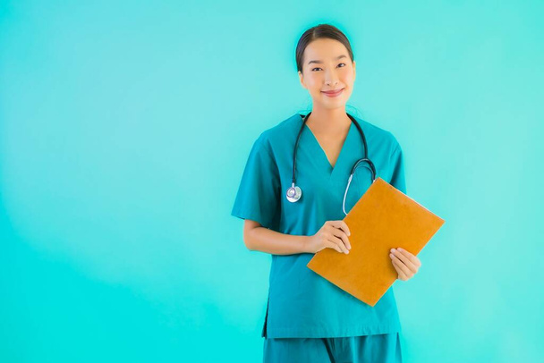 Portrait beautiful young asian doctor woman with empty paper board for copy space on blue isolated background - Healthcare in hospital and clinic concept - Foto, afbeelding