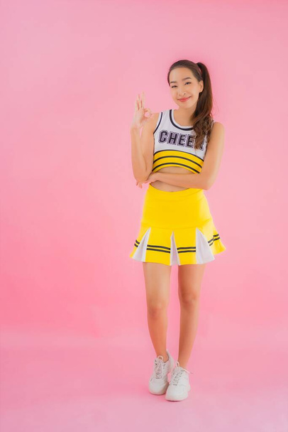 Portret mooie jonge aziatische vrouw cheerleader op roze geïsoleerde achtergrond - Foto, afbeelding