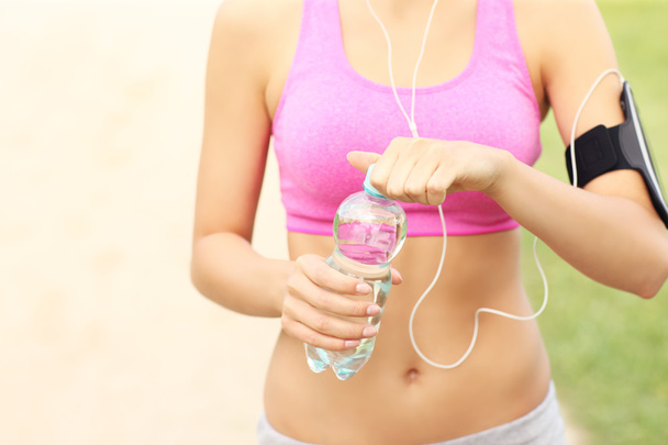 Midsection of a jogger opening bottle of water - Photo, Image
