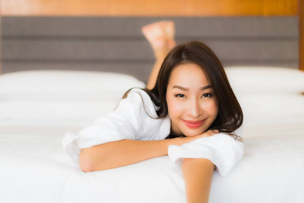 Ritratto bella giovane donna asiatica rilassarsi sorriso sul letto in camera da letto interno - Foto, immagini
