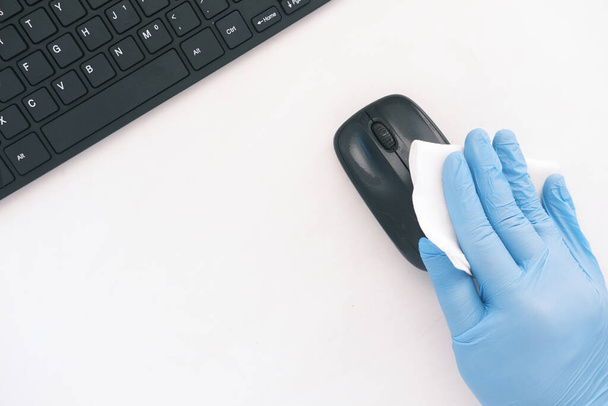 hand in blue rubber gloves and white tissue disinfecting computer mouse  - Foto, imagen