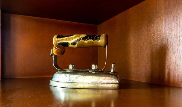 старий невикористаний одяг залізо, розміщене як прикраса на шматочку меблів в будинку
 - Фото, зображення