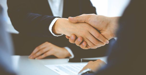 Businesspeople or lawyers shaking hands finishing up a meeting in blue toned office , close-up. Success at negotiation and handshake concepts - Photo, Image