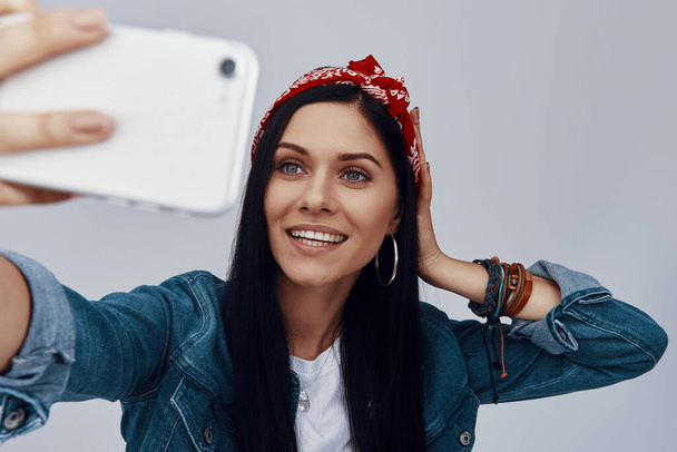 Beautiful young woman in bandana making selfie and smiling - Foto, Imagem