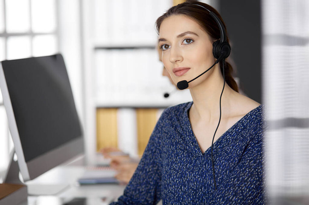 Asian or Latin american businesswoman talking by headset while sitting in office. Call center and diverse people group in business - Fotoğraf, Görsel