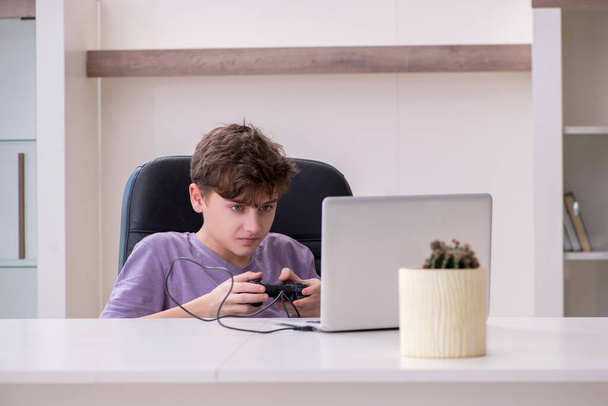 Schoolboy playing computer games at home - Foto, afbeelding