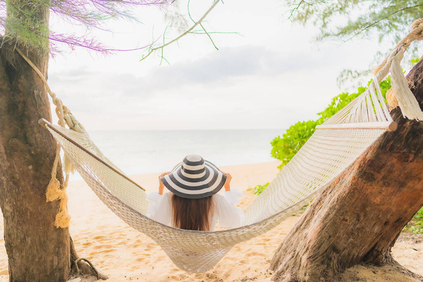 Портрет красивая молодая азиатская женщина расслабиться на гамаке вокруг пляжа море океан для отдыха в отпуске - Фото, изображение