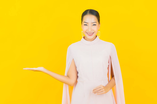 Ritratto bella giovane donna asiatica sorriso con molti azione su sfondo giallo - Foto, immagini