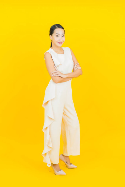 Portret mooie jonge aziatische vrouw glimlach met actie op gele kleur achtergrond - Foto, afbeelding