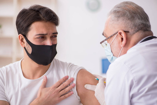 Fiatal férfi beteg meglátogatja idős orvos vakcinázás koncepció - Fotó, kép