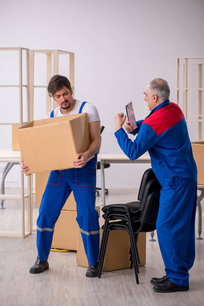 Twee mannelijke professionele verhuizers doen home relocation - Foto, afbeelding