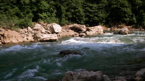 水平4kビデオスローモーション.大きな石の間で峡谷の青みがかった色合いの美しい嵐の山の川。背景に濃い緑の落葉樹林. - 映像、動画