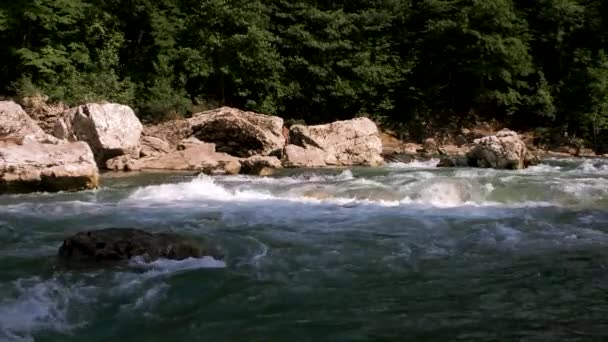 水平ズーム4kスローモーションビデオ.大きな石の間で峡谷の青みがかった色合いの美しい嵐の山の川。背景に濃い緑の落葉樹林. - 映像、動画
