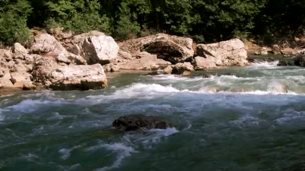 水平ズーム4kスローモーションビデオ.大きな石の間で峡谷の青みがかった色合いの美しい嵐の山の川。背景に濃い緑の落葉樹林. - 映像、動画