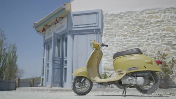 Retro scooter op de achtergrond van de Italiaanse straat. Actie. Vintage gele scooter op Europese straat op hete zomerdag. Stedelijk landschap op Europese straat met scooter - Video
