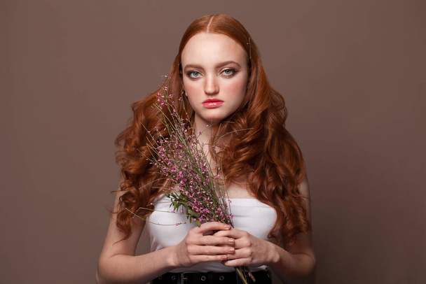 Spring woman portrait. Redhead woman holds flowers - Fotó, kép