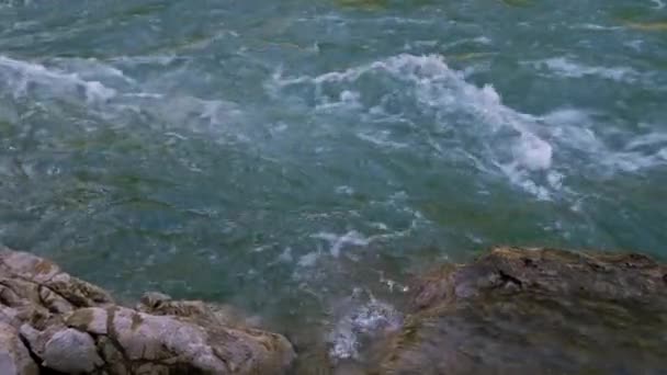 青い色合いの美しい嵐の山の川が急速に大きな石や岩の間を閉じる流れます。山の川は魅力的で注目を集めています。水平4kリアルタイムビデオ. - 映像、動画