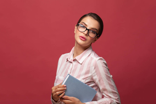 Woman in glasses holding book on red background - Φωτογραφία, εικόνα