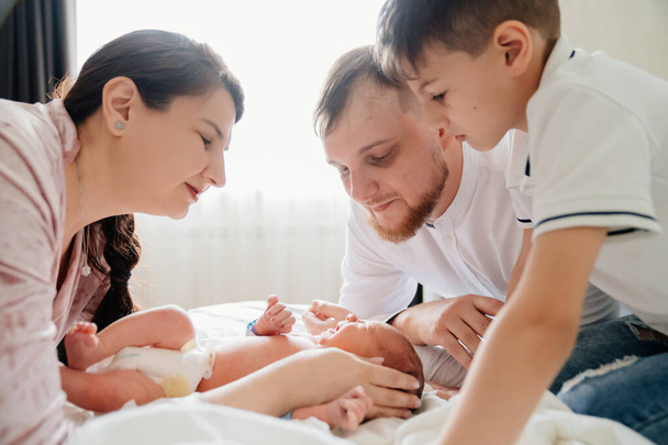 first day of newborn at home. Happy family looking at the newborn in the bedroom - Photo, image