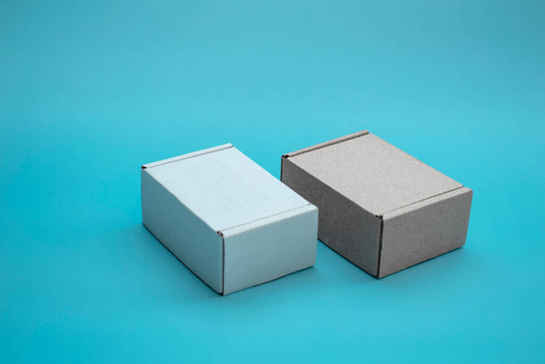 Nahaufnahme von Pappschachteln mit Kopierraum. Zwei Corton-Boxen: braun und weiß auf blauem Hintergrund. Konzept für Verpackung, Geschenke, Lieferung. - Foto, Bild